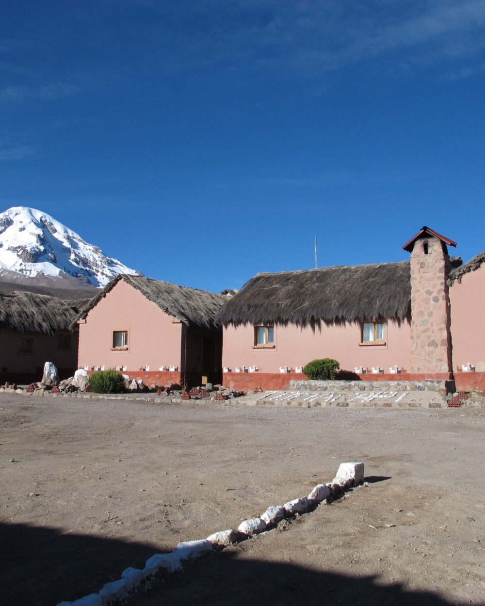 Cour de l'écolodge en adobe de Tomarapi face au Nevado Sajama enneigé