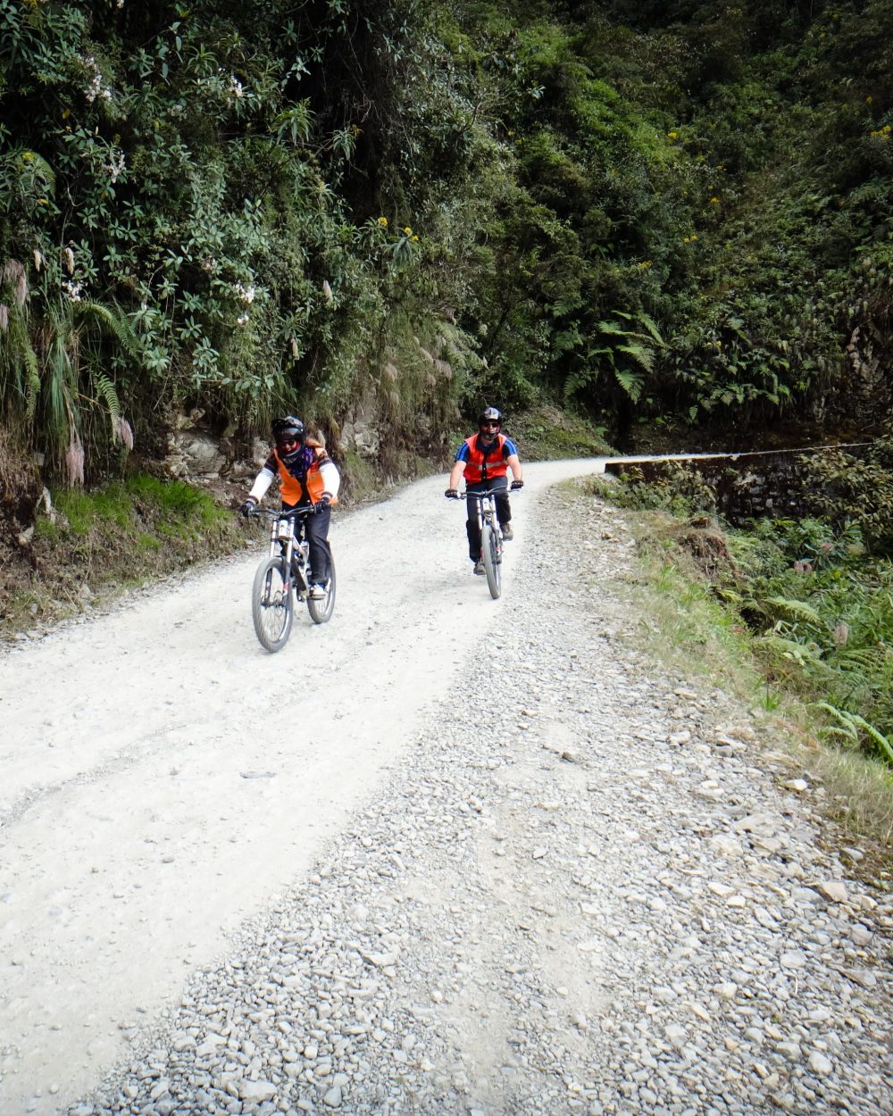 Deux vététistes descendant la Route de la Mort sur une piste de gravier au cœur de la végétation tropicale des Yungas